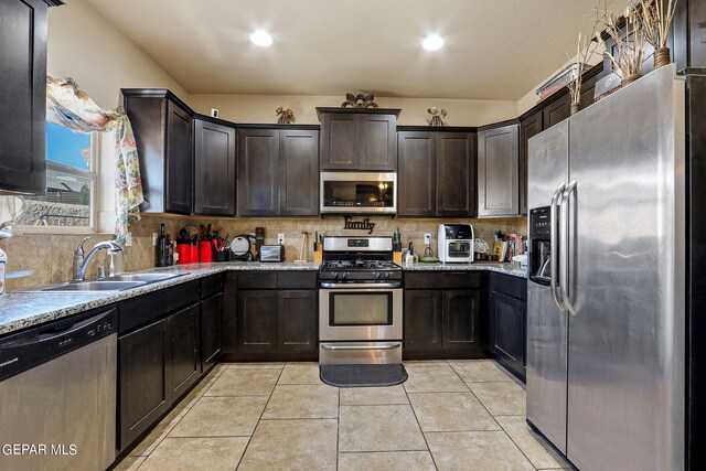 kitchen featuring light stone countertops, stainless steel appliances, tasteful backsplash, and sink