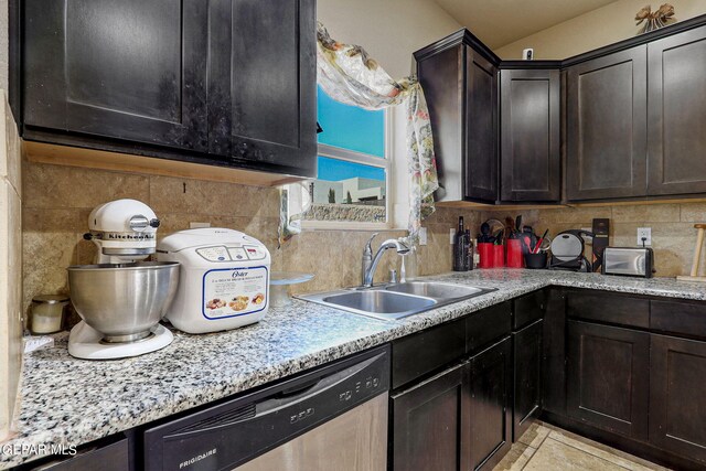 kitchen featuring tasteful backsplash, sink, light tile patterned floors, dark brown cabinetry, and stainless steel dishwasher