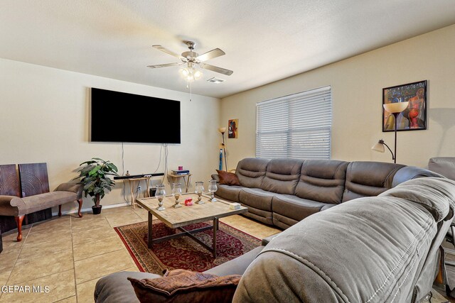 living room featuring a textured ceiling, light tile patterned floors, and ceiling fan