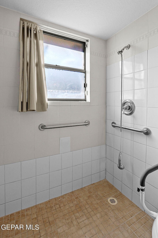 bathroom with a tile shower and a textured ceiling