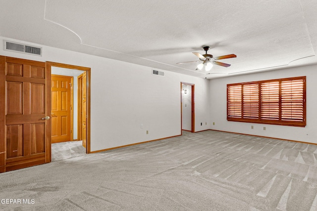 carpeted spare room featuring ceiling fan and a textured ceiling