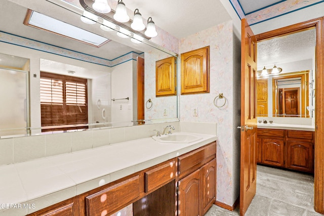 bathroom with a textured ceiling, vanity, and a skylight