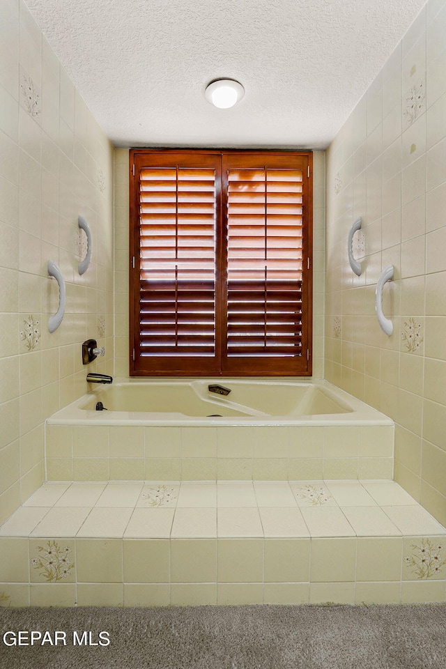 bathroom featuring tile walls, a textured ceiling, and a relaxing tiled tub