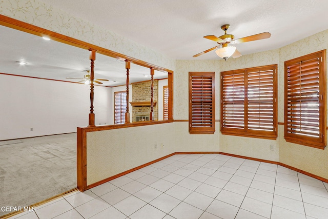 empty room featuring ceiling fan, a textured ceiling, a fireplace, and light carpet