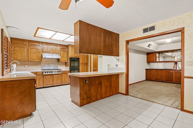 kitchen with ceiling fan, sink, kitchen peninsula, stainless steel gas cooktop, and light colored carpet