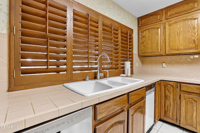 kitchen with tile counters, dishwasher, sink, and light tile patterned floors