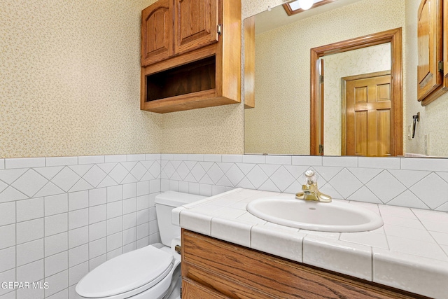 bathroom featuring tile walls, vanity, and toilet