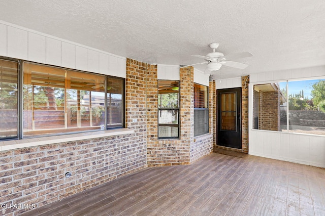 unfurnished sunroom with ceiling fan