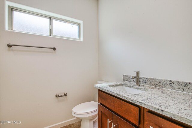 bathroom with a wealth of natural light, wood-type flooring, vanity, and toilet