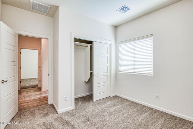 unfurnished bedroom featuring a closet and light colored carpet