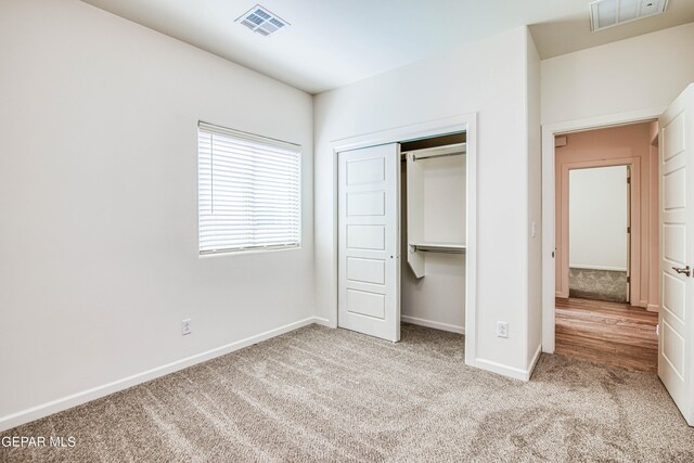 unfurnished bedroom featuring light carpet and a closet