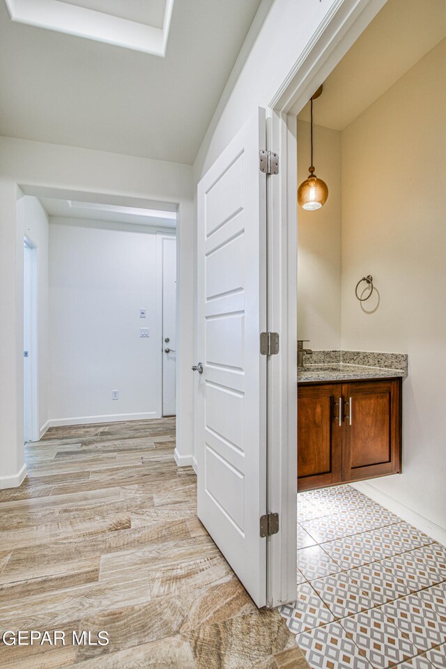 corridor featuring light wood-type flooring and sink