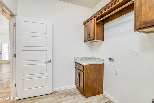 clothes washing area with washer hookup, light hardwood / wood-style flooring, and cabinets