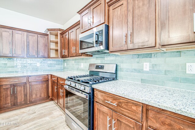 kitchen with light stone countertops, appliances with stainless steel finishes, light hardwood / wood-style floors, and tasteful backsplash