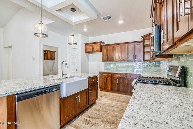 kitchen with appliances with stainless steel finishes, backsplash, light stone countertops, decorative light fixtures, and sink