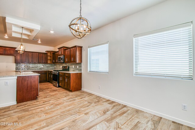 kitchen with light stone counters, pendant lighting, appliances with stainless steel finishes, and light wood-type flooring