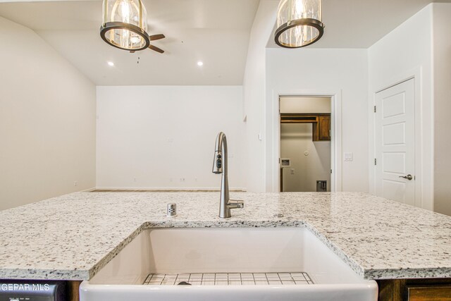 kitchen featuring hanging light fixtures, sink, ceiling fan, and light stone counters