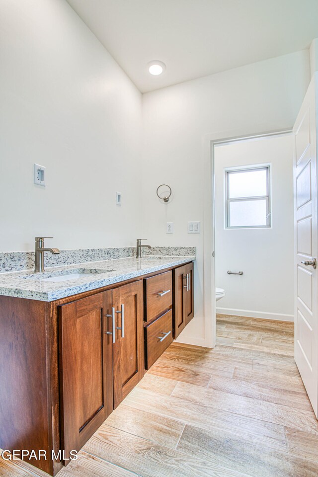 bathroom featuring wood-type flooring, vanity, and toilet