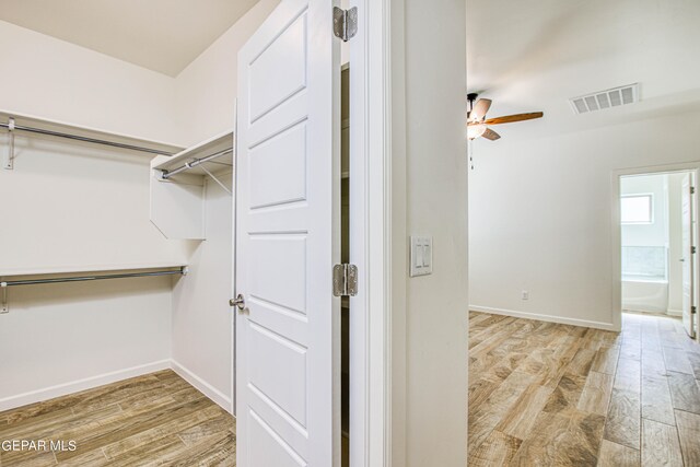 spacious closet with ceiling fan and light hardwood / wood-style floors