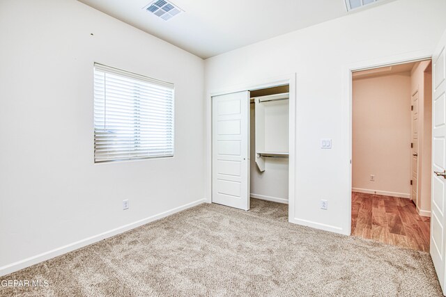 unfurnished bedroom with light colored carpet and a closet