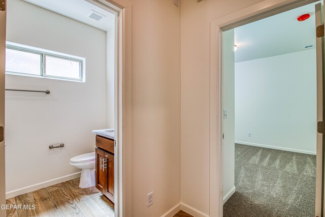 bathroom with hardwood / wood-style flooring, vanity, and toilet