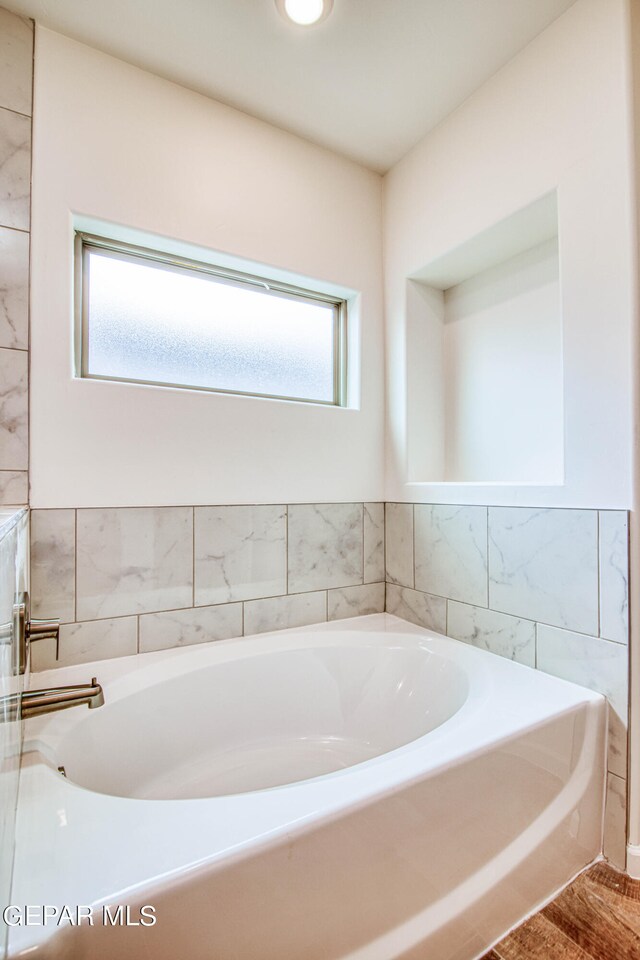 bathroom with tile walls, plenty of natural light, and a bathtub