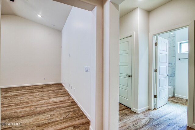 hallway featuring vaulted ceiling and light hardwood / wood-style floors