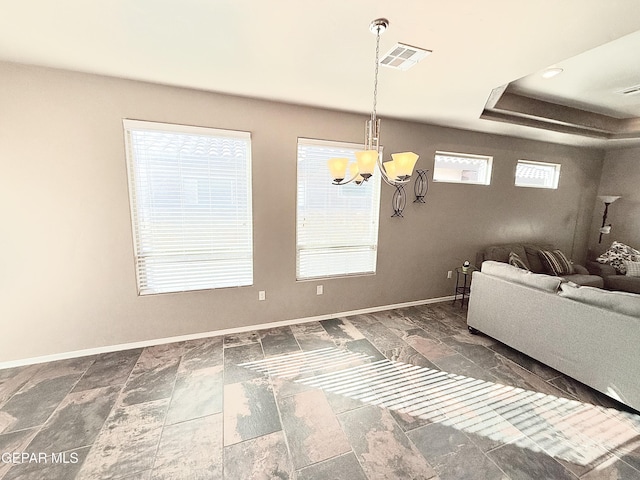 living room with an inviting chandelier and a tray ceiling