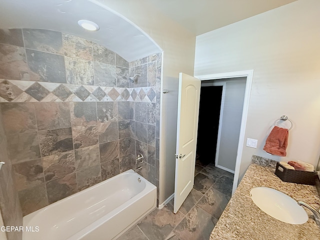 bathroom featuring vanity, tiled shower / bath combo, and vaulted ceiling