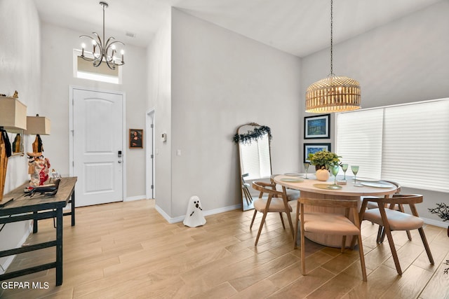 dining space with a high ceiling, a chandelier, and light wood-type flooring