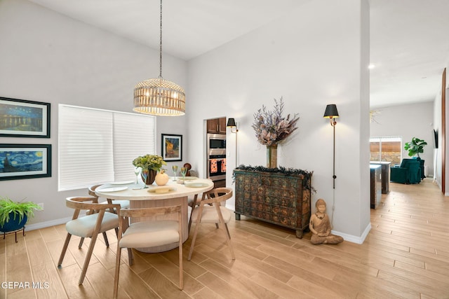 dining room with a high ceiling, an inviting chandelier, and light wood-type flooring