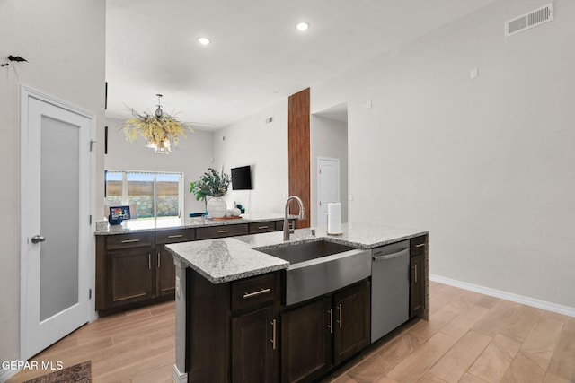 kitchen featuring a kitchen island with sink, light hardwood / wood-style flooring, sink, light stone counters, and dishwasher