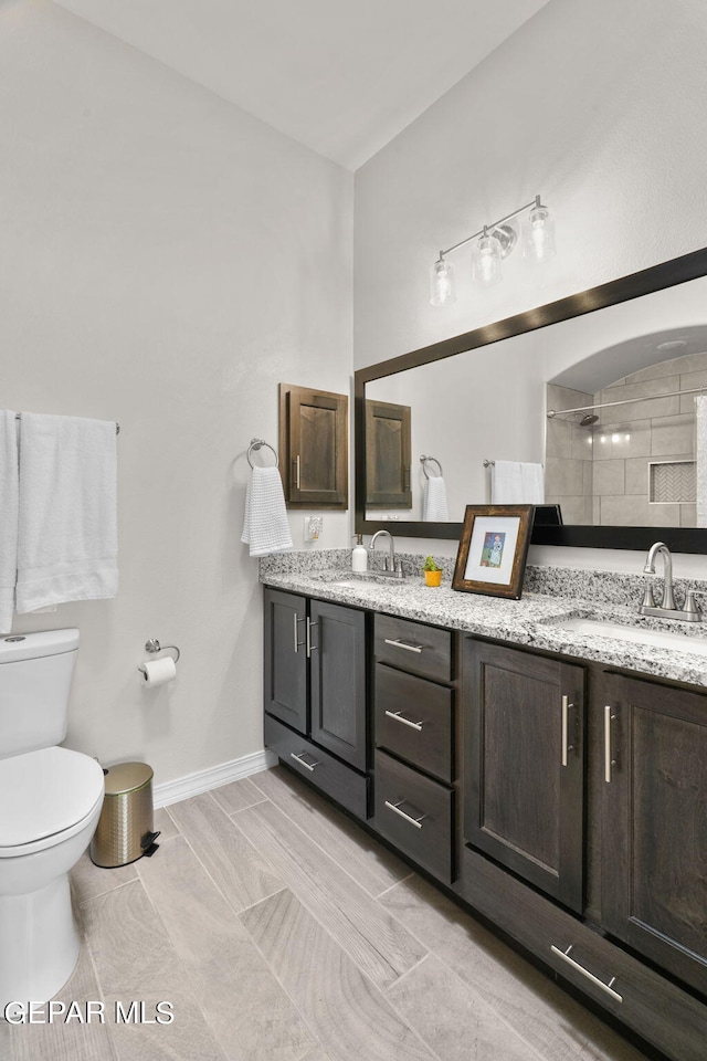 bathroom featuring a tile shower, vanity, and toilet