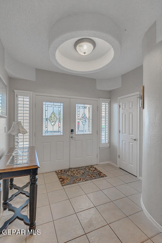 entrance foyer with a textured ceiling, a healthy amount of sunlight, and light tile patterned floors