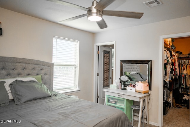 bedroom with ceiling fan, light colored carpet, a closet, and a walk in closet