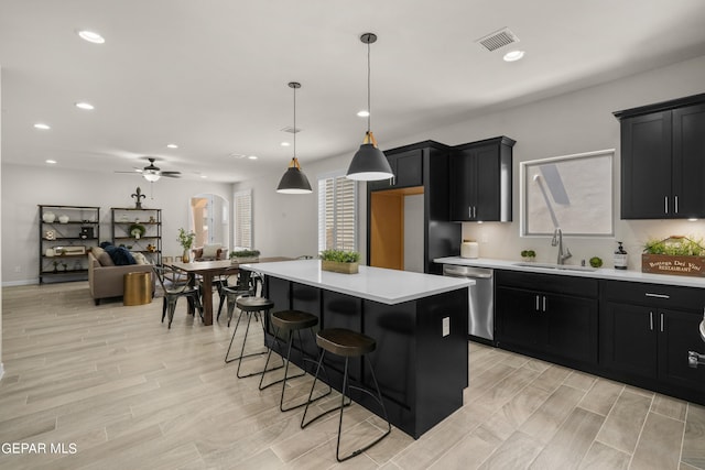 kitchen with dishwasher, light hardwood / wood-style flooring, hanging light fixtures, and a kitchen island