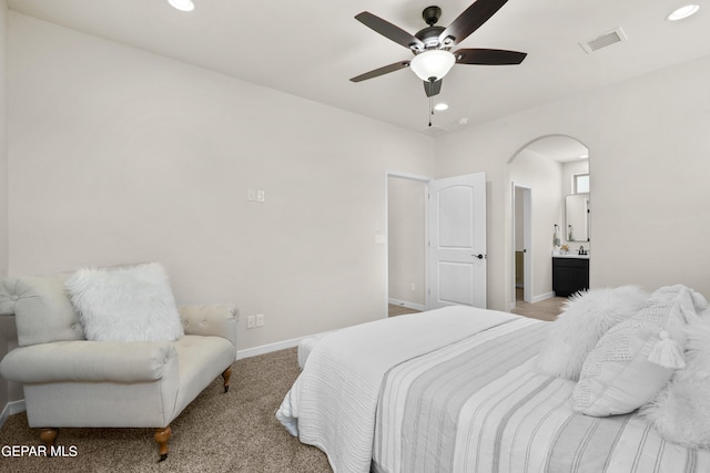 carpeted bedroom with ensuite bath and ceiling fan