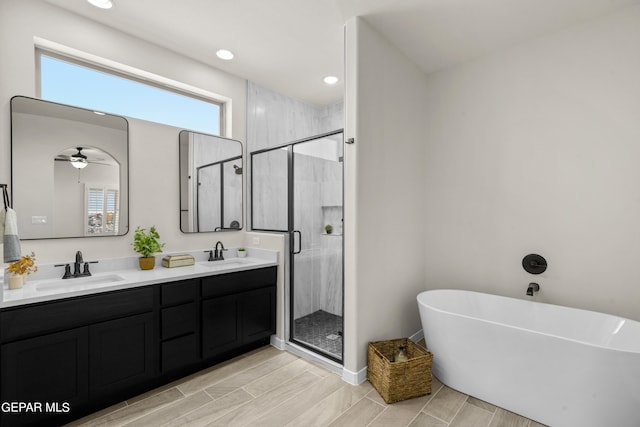 bathroom with independent shower and bath, vanity, ceiling fan, and wood-type flooring