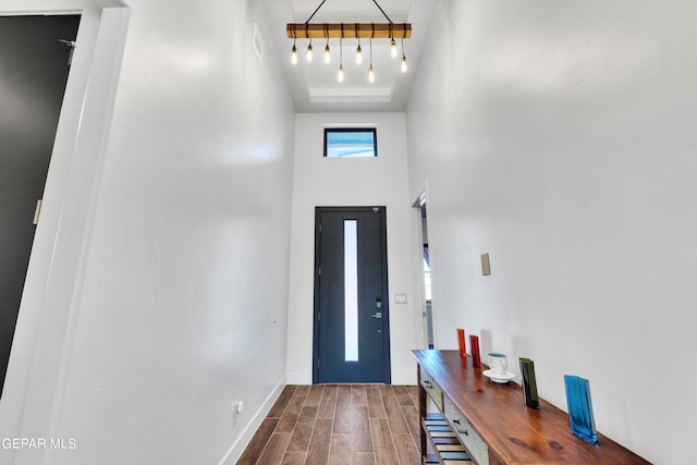 entrance foyer with track lighting, a towering ceiling, and dark hardwood / wood-style flooring