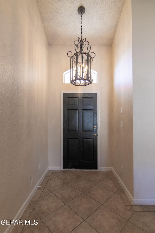 entryway featuring an inviting chandelier, tile patterned floors, and a textured ceiling