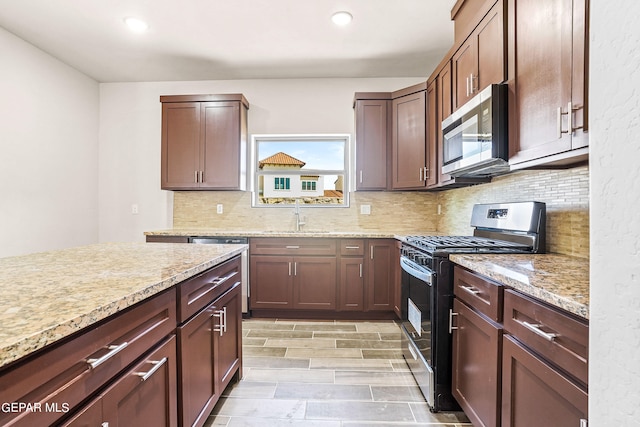 kitchen with light stone counters, tasteful backsplash, sink, light hardwood / wood-style flooring, and stainless steel appliances