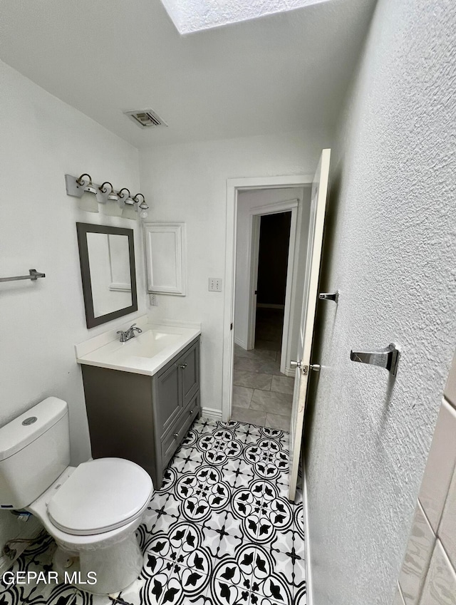 bathroom featuring vanity, tile patterned flooring, and toilet