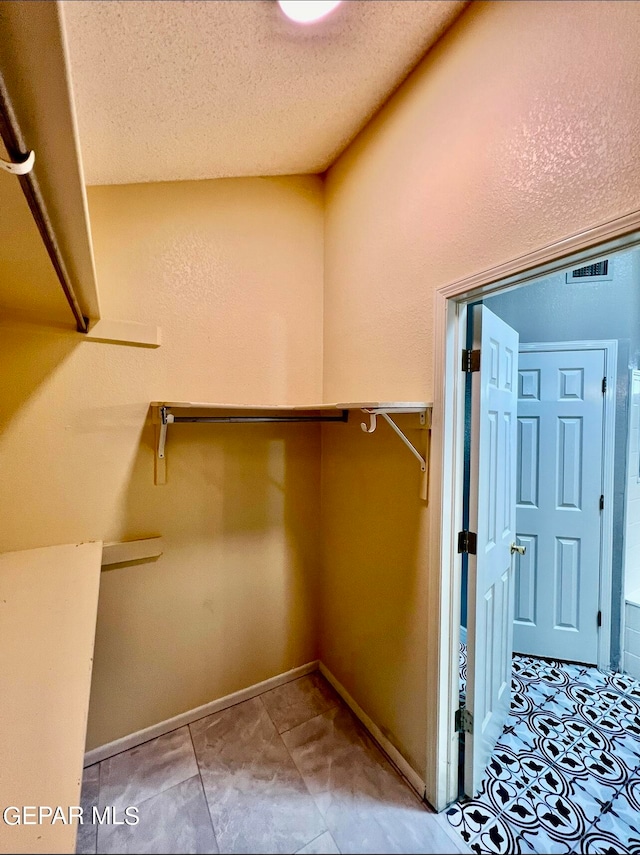 walk in closet with light tile patterned floors