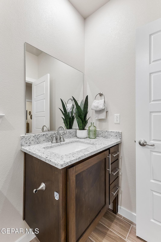 bathroom with wood tiled floor, vanity, and baseboards