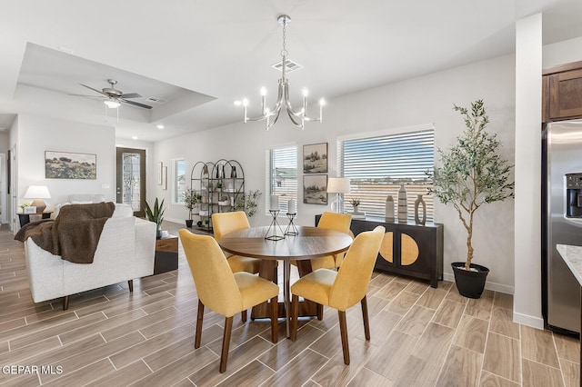 dining space with wood finish floors, a raised ceiling, visible vents, and baseboards