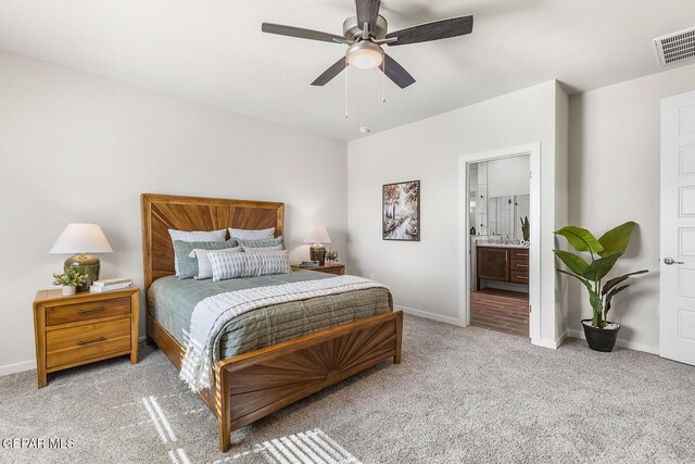 bedroom featuring ensuite bathroom, light colored carpet, a ceiling fan, baseboards, and visible vents