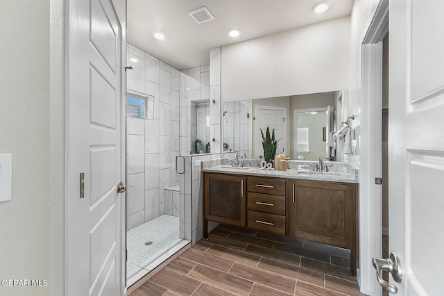 full bath with a stall shower, wood finish floors, visible vents, and a sink