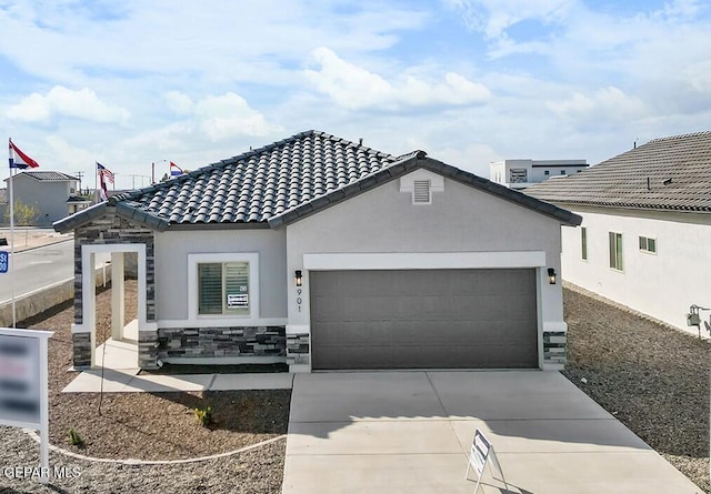 view of front facade with driveway, an attached garage, a tile roof, and stucco siding