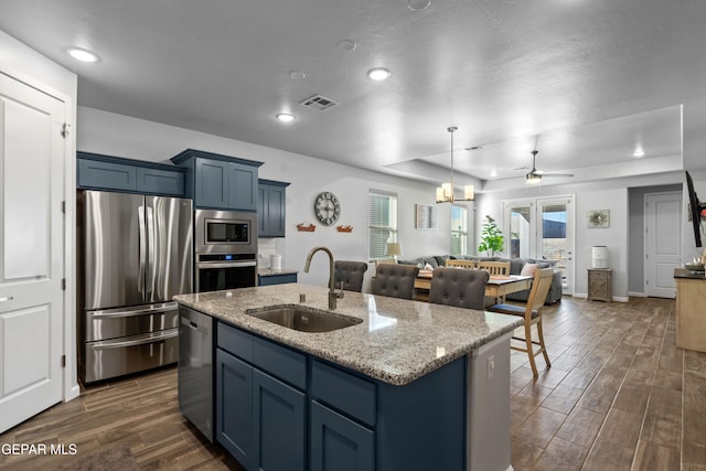 kitchen featuring an island with sink, appliances with stainless steel finishes, dark hardwood / wood-style floors, and sink