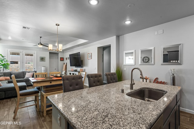 kitchen featuring pendant lighting, a center island with sink, dark wood-type flooring, and sink